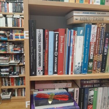 zdjęcie przedstawia książki na półkach szafek bibliotecznych, różnokolorowe grzbiety okładek ustawionych w pionie