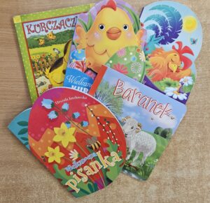 Zdjęcie przedstawia 5 kolorowych książek dziecięcych o Wielkanocy. Książki ułożone są na drewnianej powierzchni. 